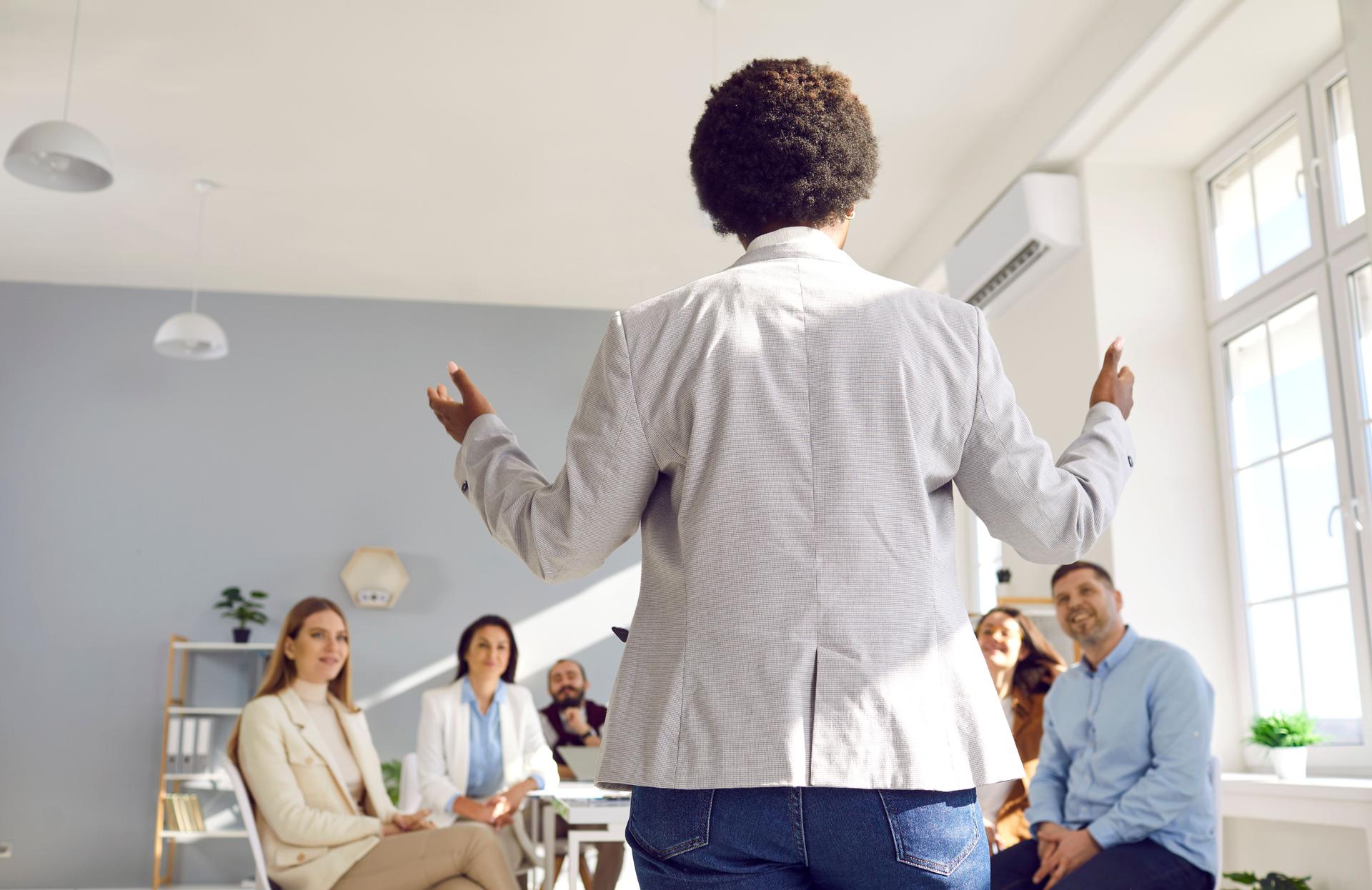 Back view of Black woman making speech for business team during meeting in office